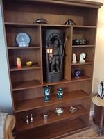 Front view of solid wood bookcase/display unit with multiple shelves and decorative items shown