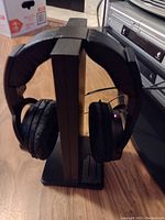 Sony cordless over-ear headset resting on black vertical charging station with indicator light on, showing it is charging or powered.