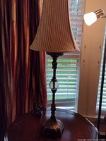 Full view of the bronze-colored metal table lamp with fabric shade, showing overall design and structure.