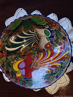 Top view showing vibrant bird designs inside the terracotta bowl with a scalloped blue rim.