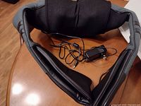 Front view of the wireless shiatsu massager showing the body and attached power adapter with cable.