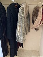 Side view of two Persian Lamb coats hanging, one black and one with mink collar