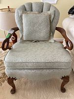 Front view of fabric arm chair with matching pillow on seat, showing upholstery pattern and wood armrest details.