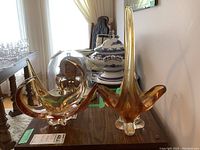 Two amber Chalet art glass pieces placed on a wooden surface.