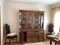 Full front view of Bassett buffet and hutch set in room with chairs and tableware, showing glass doors and wood finish.