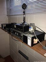 MFJ tuner, CB radio, microphone and speaker on wooden shelf