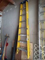 Full view of yellow fiberglass ladder leaning against a wall
