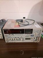 Front view of bench instrument showing frequency counter and multimeter displays with cleaning kit and probe cable on top