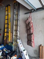 Yellow fiberglass multi-position ladder and silver aluminum extension ladder leaning in garage.