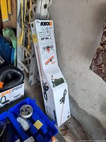 Photo showing boxed WORX electric hedge trimmer leaning against wall and ladder.