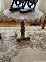 Marble table with ornate metal stand and square scalloped marble top with pink and white veining.
