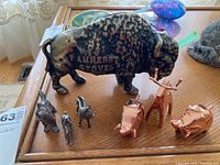 Photo showing the full set of metal animal figures with the Amherst Stoves buffalo coin bank and smaller animal figures including silver-tone cat, dog, rabbit, and copper-tone Umbra elephants and deer.