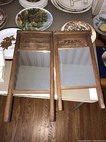 Two vintage washboard-style wooden framed mirrors side-by-side on a table showing their full rectangular shape and identifying markings.