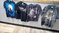 Four vintage animal-themed T-shirts hanging on hangers, showing wolf and eagle graphics.