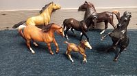Photo showing 5 large Breyer original model horses and 1 small foal horse arranged on carpet against wall background, highlighting colors and poses of each model horse.
