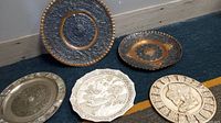 Overview of five decorative metal plates on floor depicting Mayan, Aztec calendars and Chinese art with mother of pearl inlay