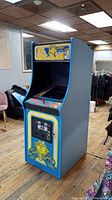 Front left three-quarter view of blue Ms. Pac-Man arcade cabinet showing marquee, control panel and side graphics.