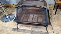 Front view of the outdoor heavy metal firepit cage with mesh sides and arched top cover.