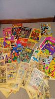 Wide view of the assortment of vintage comic books, showing a variety of titles and worn condition.