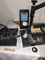 Photo of black ASC365 3-in-1 heat press showing control panel with digital display and mug attachment in heating position.