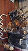 Photo showing metal table fan, Keurig coffee machine, wooden coat hanger rack, and metal wine bottle holder all arranged on a table.