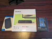 Closed box of Sony Blu-ray/DVD player, Eton weather radio in packaging, and Kensington USB-C dock box