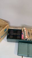 View showing green plastic storage box with black View-Master viewer inside and stacks of image reels/disks.