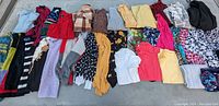 All items laid out side by side showing an array of women’s sweaters and shirts with various colors and patterns.
