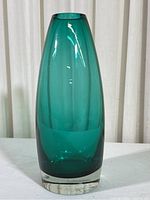 Front view showing full teal colored glass vase with thick clear base.