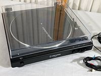 Turntable with dust cover closed, showing product and power/cable connections.