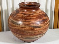 Front view of round pottery vase with brown and tan horizontal glazing pattern, glossy finish