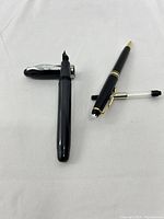 Two pens shown with caps off and ink cartridge beside them on a white background.