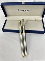 Pair of Waterman Paris fountain pens with silver curved barrels and gold accents in original blue case.