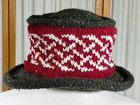 Front and sides view of the novelty souvenir wool hat from Old Bushmills Irish Whiskey with red and white knitted band and dark textured wool brim and crown.