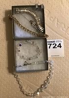 Photo of four bracelets including rhinestone bracelets, a gold-tone metal bracelet, and clear crystal bead bracelets arranged in two boxes.