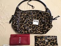 Leopard print handbag with black handles and silver Brighton logo, next to red wallet with silver buttons