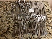 Full set showing forks, spoons, and knives arranged on granite countertop