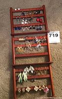 Full view of earring variety on wooden rack, shows assortment of studs, hoops, drops in multiple colors and materials.