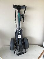 Fairway Flyer golf cart in folded state, showing wheels and carrying strap.