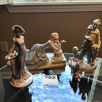 Set of three porcelain figurines displayed on glass table showing overall lot contents