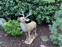 Large buck deer statue in front of shrub backdrop