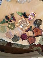 Overview of items showing glass leaf plates, ceramic turkey bowl, wine cork holder, wooden cork tray, and artificial grape bunches on table.