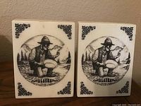 Front view of the white marble Alaska-themed bookends with prospector illustration and decorative corner designs.