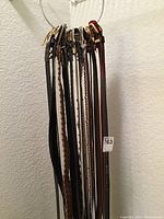 Photo showing a collection of various ladies belts hanging on a white rack. The belts are of different colors including black, brown, tan, red, and multi-colored. Various buckle styles are visible.