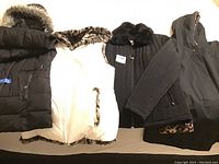Four ladies heavy jackets laid out, various colors including black and white, various fur and leopard print details.