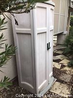 Closed resin vertical storage shed positioned outdoors.