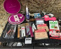 Full view of all items on granite countertop including Norelco Ladybug device with case, mascara, lashes, nail tools, and other beauty items.