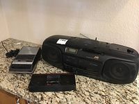 Panasonic cassette recorder, JVC boombox, and another small audio device on granite surface.