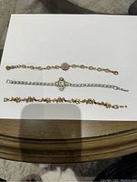 Photo of three bracelets laid out on a white paper background showing details and arrangement of each bracelet from left to right.