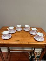 Full view of 6 demitasse cups and 6 matching saucers arranged on wooden table, showing overall set